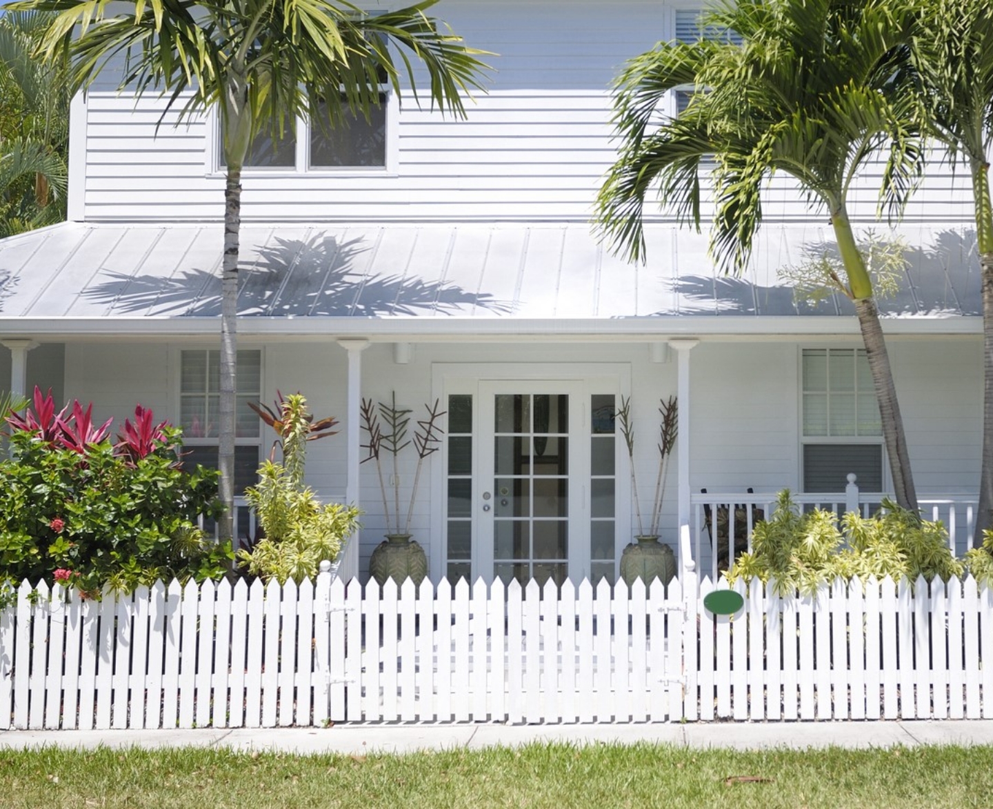 home with palm trees and white picket fence