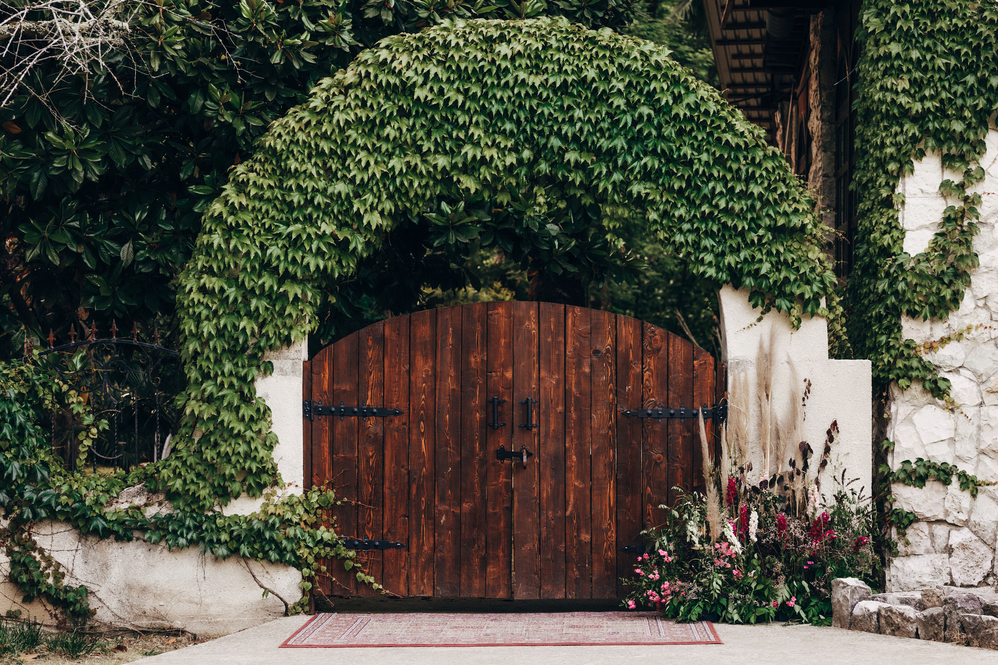 The beautiful old gate, decorated with a floral arrangement and overgrown with ivy