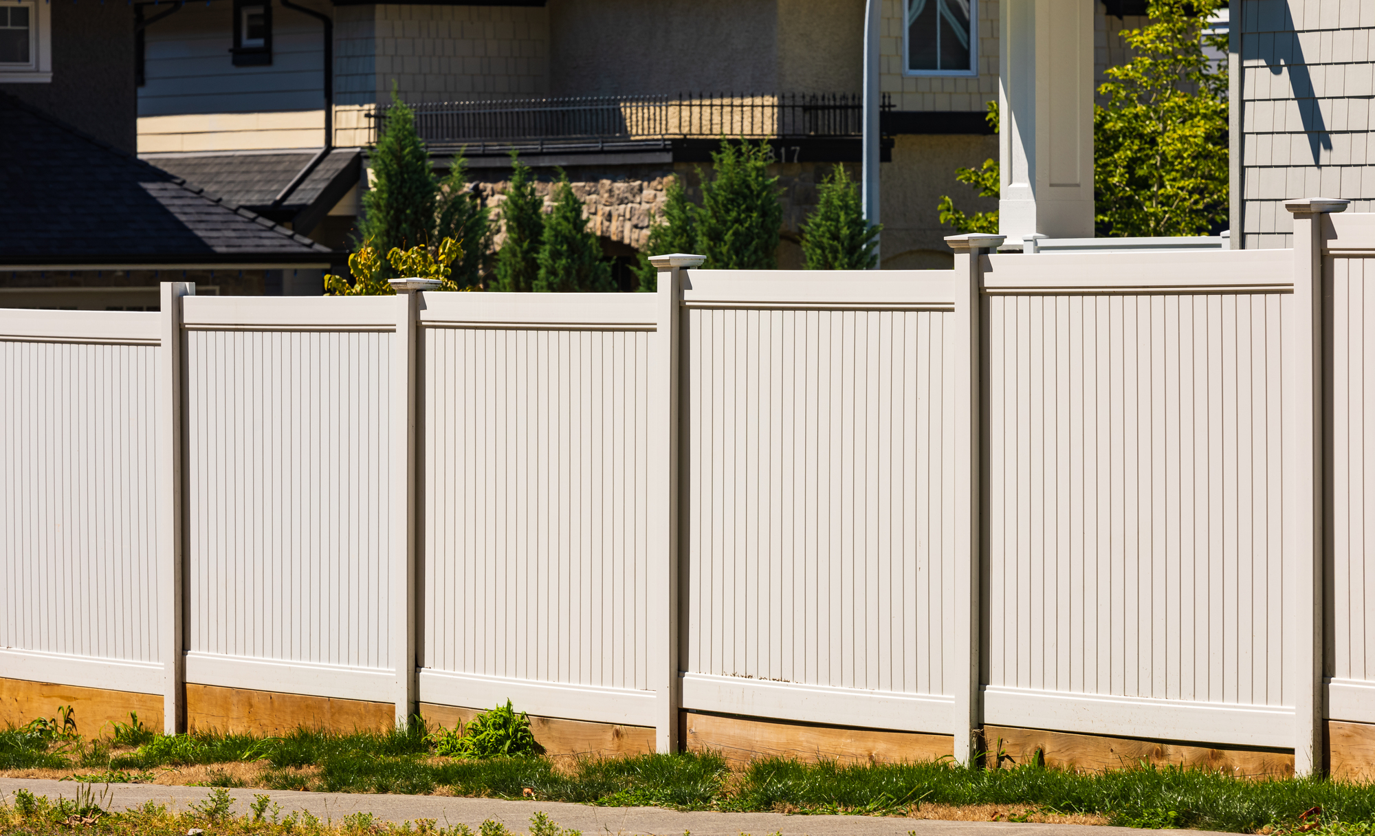 White vinyl picket fence on green lawn surrounding property