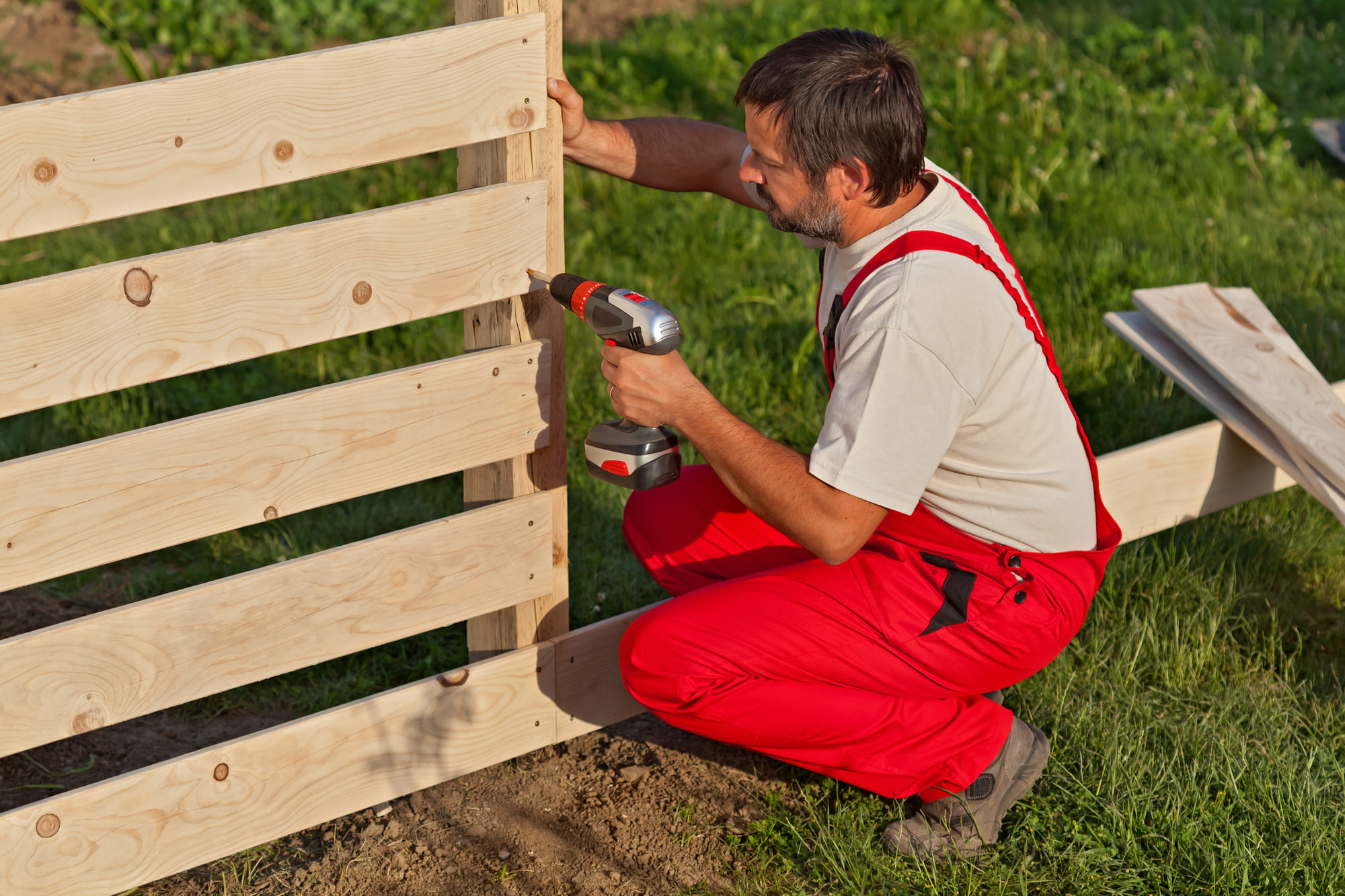 man building a horizontal wooden fence