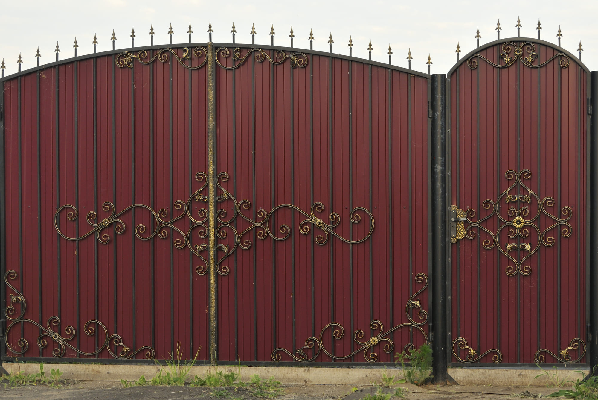 Ornate and beautiful wrought iron fence gate painted scarlet red and gold