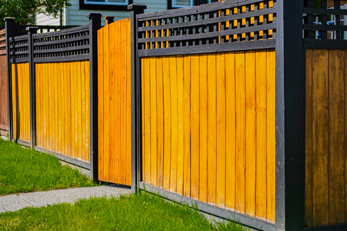 A wooden privacy fence with with wooden gate with green lawn