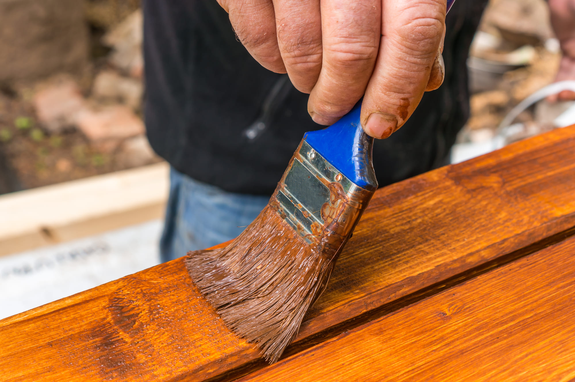 staining a wood fence with paint brush